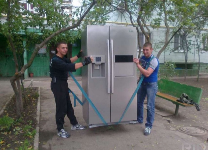 Двоє вантажників несуть пральну машину сходами